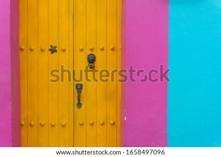 Yellow Wooden Doors in vibrant coloured wall in Old town of Cartagena, Colombia. High Resolution Image.