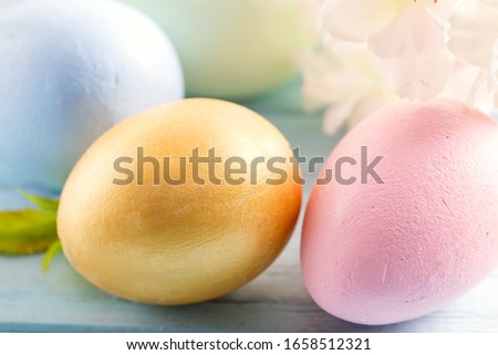 Greeting Easter card with close-up handmade painted eggs and tender flowers on a light blue background.