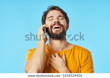 A man in a yellow T-shirt is talking on the phone