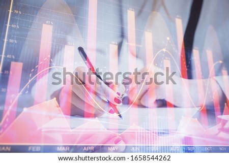 Double exposure of hands making notes with forex chart huds. Stock market concept.