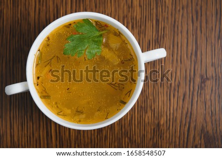 A picture of a bowl of traditional chicken soup served in a bowl over wooden background