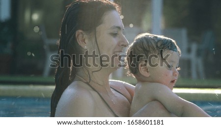 
Mother playing with baby child boy at the pool
