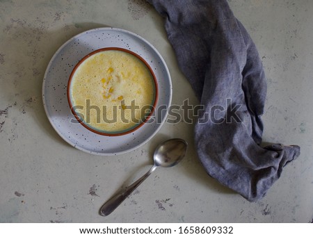 Delicious creamy yellow corn soup on rustic pastel background. Menu of the day