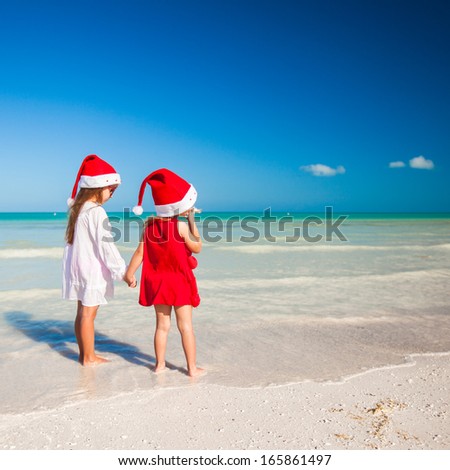 Rear view of Little cute girlsÃ?Â in Christmas hats on the exotic beach