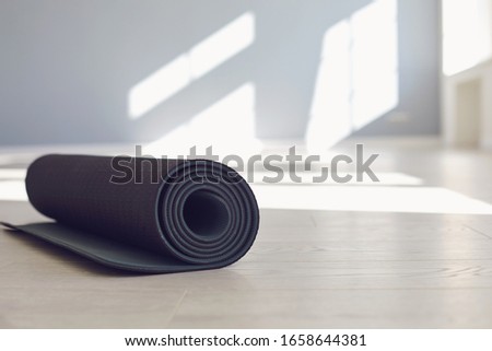 Black yoga mat on the floor of a bright sunny studio. Royalty-Free Stock Photo #1658644381