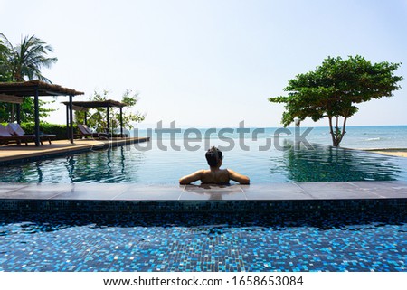 A man sitting at the pool watching the beach view by the sea
