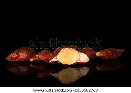 Group of five whole one half of exotic brown salak isolated on black glass