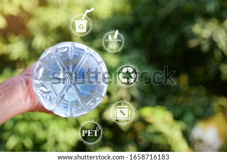 Hand holding PET plastic bottle.Show PET sign at bottom of bottle,recycle icon,picking up Plastic Bottle,PET icon and Yarn icon.Save environment concept