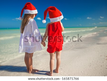 Little cute girlsÃ?Â in Christmas hats on the exotic beach