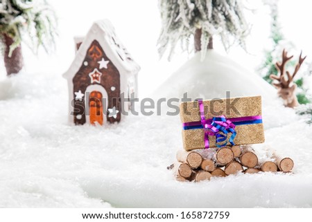 A Christmas Gift stacked on a snowy woodpile within a winter landscape.