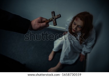 exorcist holding cross in front of obsessed girl Royalty-Free Stock Photo #1658730559
