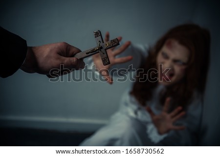 selective focus of exorcist holding cross in front of yelling obsessed girl Royalty-Free Stock Photo #1658730562
