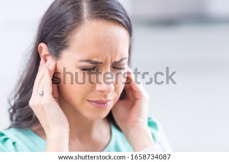 Young woman have headache migraine stress or tinnitus - noise whistling in her ears. Royalty-Free Stock Photo #1658734087