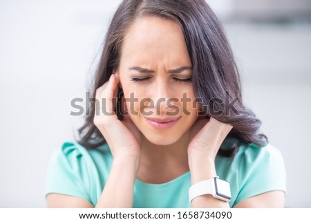 Young woman have headache migraine stress or tinnitus - noise whistling in her ears. Royalty-Free Stock Photo #1658734090