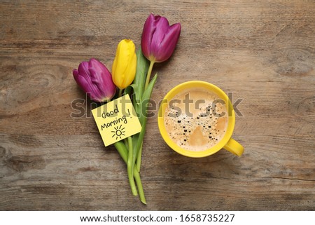 Delicious coffee, flowers and card with GOOD MORNING wish on wooden table, flat lay