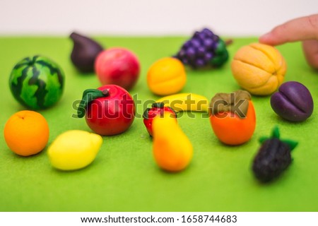 A child plays with polymer clay toy fruits