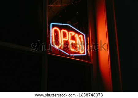 Red open neon sign glowing in the night.