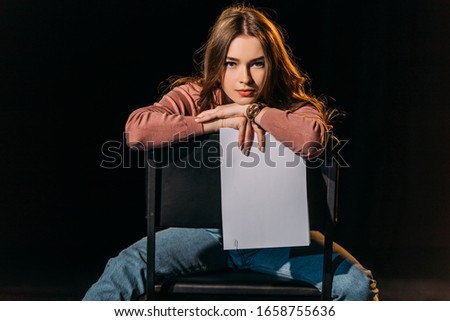 attractive young actress with scenario sitting on chair on stage in theatre Royalty-Free Stock Photo #1658755636