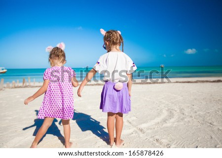 Two little cute girls in easter ears have fun on the exotic beach