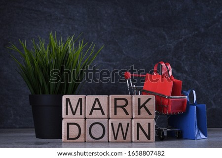 Shopping concept. Wooden cubes with word mark down on the dark background with shopping basket