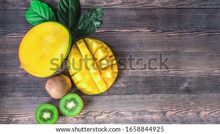 mango and kiwi on a wooden background top view. the mango and kiwi halves lay flat on the table. fruit and copy space.