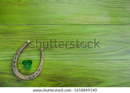 Horseshoe and clover on green wooden background. Green leaf clover. Saint Patrick's day symbol.