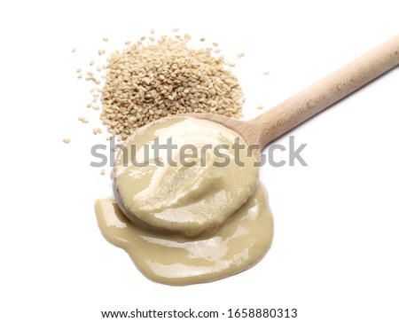 Nut butter or sesame paste tahini in wooden spoon and organic integral sesame seeds isolated on white background Royalty-Free Stock Photo #1658880313