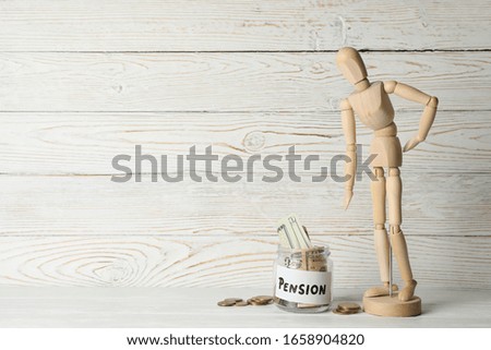 Wooden man and jar with money on wooden background, space for text