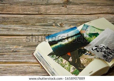 Photo album and strewn colorful various photographs on a wooden table