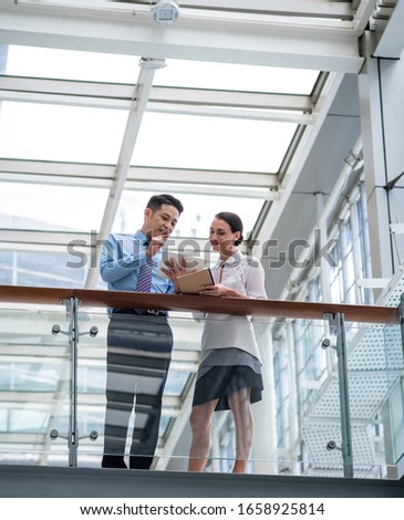 Talking strategy before the meeting stock photo.Shot of two colleagues talking together over a digital tablet while standing in a modern office