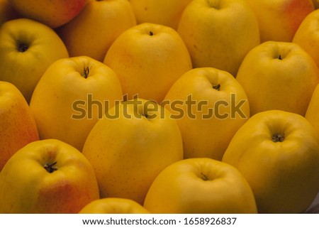 Stock photo of a close-up of a pile of delicious yellow apples at a market stall