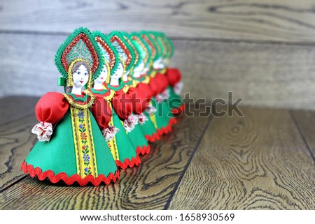 Dolls in national costumes. Sundress, kokoshnik. Green shades. Wooden background.