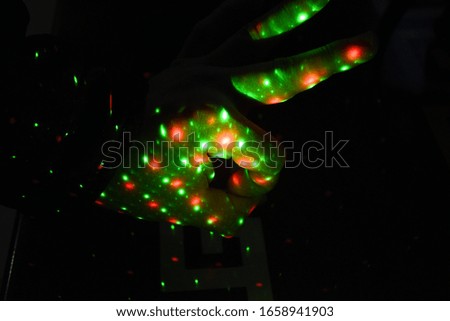 The male hand shows a figure of fingers meaning okay, and on the hand are many multicolored dots, lights. Light music is reflected on the hand, fingers.