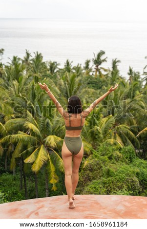 Unity with nature. Back view of a fit Caucasian female holiday-maker standing on a stone