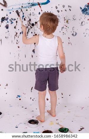 A Toddler Boy in Shorts and a Vest Painting on the Wall