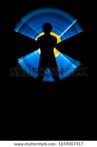 the silhouette of a human stands out against the black background, and circular waves of colored light start from him