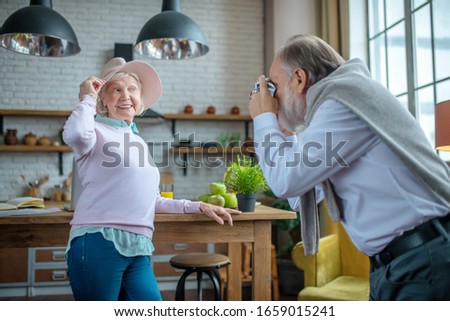 Being a model. Elderly woman posing while her husband taking pictures