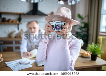 Film photography. An elderly woman wearing a hat using a film camera