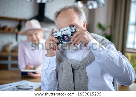 Taking pictures. A cheerful elderly man using an old film camera