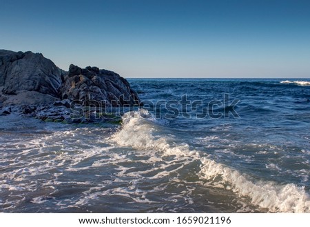 Beautiful Rock on the beach. Wave breaks into rocks