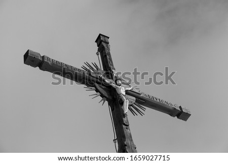 Livigno - Italy. Close up of the summit cross on a mountain at Livigno. Picture looks dramatic in grey tones and with the clouds in the background.