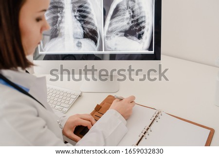 Picture of young woman doctor in hospital. Background with chest x-ray on a computer screen