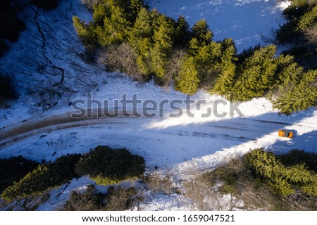 Amazing aerial view of forests and a road in winter time seen from drones
