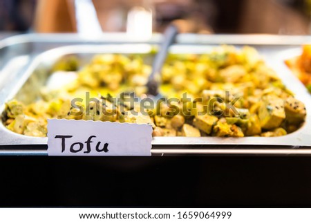 Cooked tofu cubes with vegetables in market shop grocery display in Florence Italy closeup with sign at buffet tray