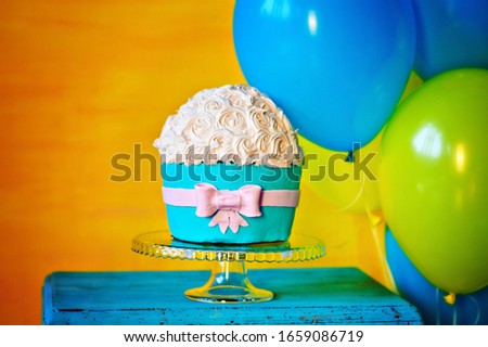 Cake with a bow on a glass plate. Yellow and blue balls.