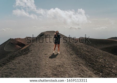 Young woman on top of a mountain photographing nature, hiking up on top of Mount Etna, photographer taking a picture