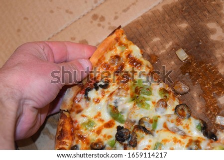 Supreme pizza being held in a hand