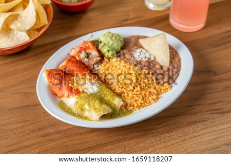 Spicy Mexican food in a restaurant. Christmas enchiladas with rice and refried beans. Royalty-Free Stock Photo #1659118207