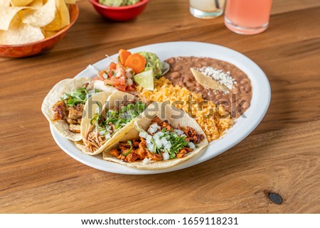 Trio taco plate with chicken, pork, and beef. Mexican food served with rice and refried beans. Royalty-Free Stock Photo #1659118231