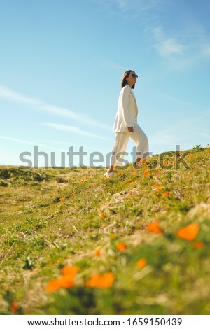 Outdoor lifestyle photo of beautiful young woman in white suit the poppy field. Freedom and independence